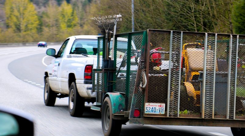 a white truck driving down a road next to a forest