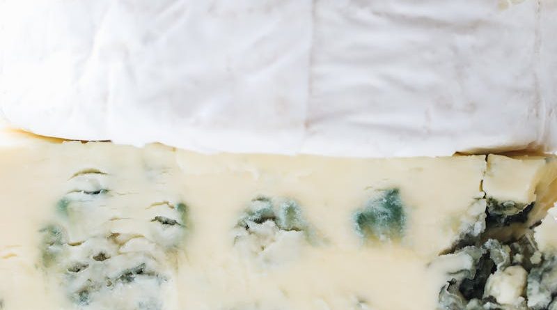 Close-up of assorted cheeses stacked with distinct textures. Ideal for gourmet food inspiration.