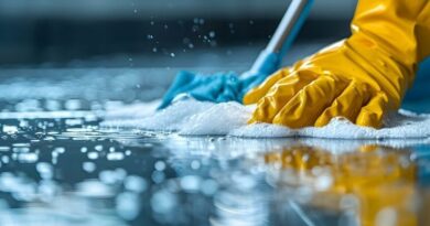 A person in yellow gloves and blue gloves cleaning a floor