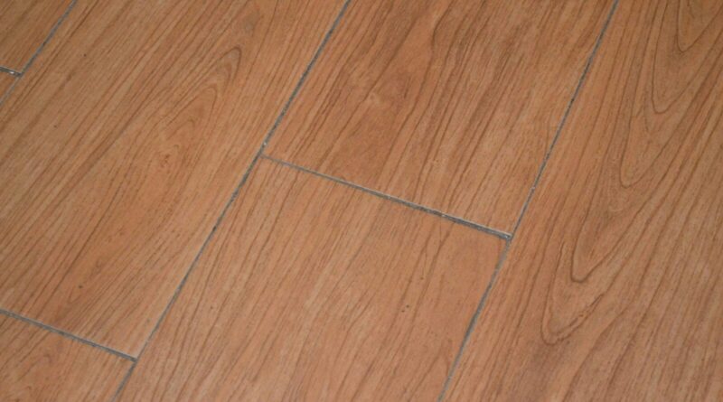a close up of a wooden floor with a white cat laying on it